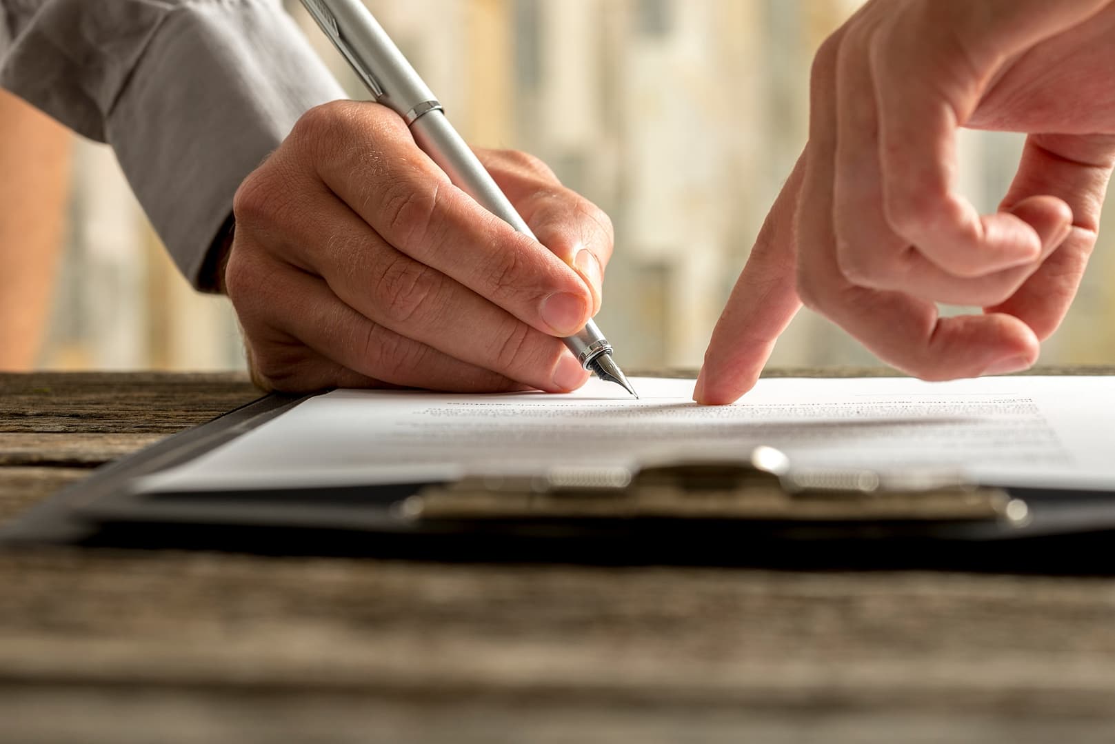Closeup of employer showing his new employee where to sign an employment contract Closeup of employer showing his new employee where to sign an employment contract